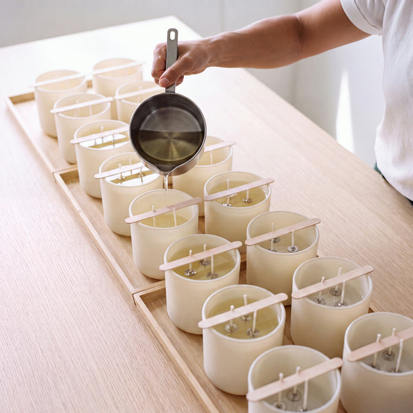 Clear molten wax being poured into Glow Guardian vessels, each with three cotton wicks