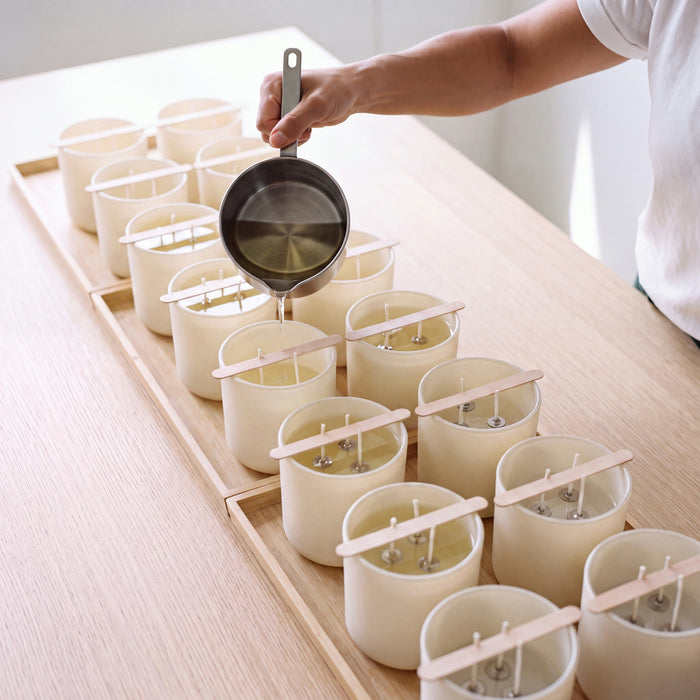 Clear molten wax being poured into Glow Guardian vessels, each with three cotton wicks