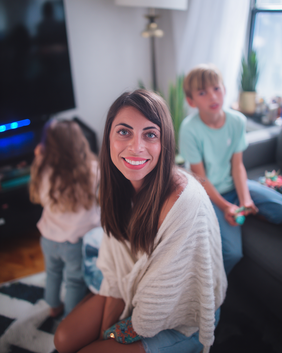 Woman sitting on a couch with two children in a living room.