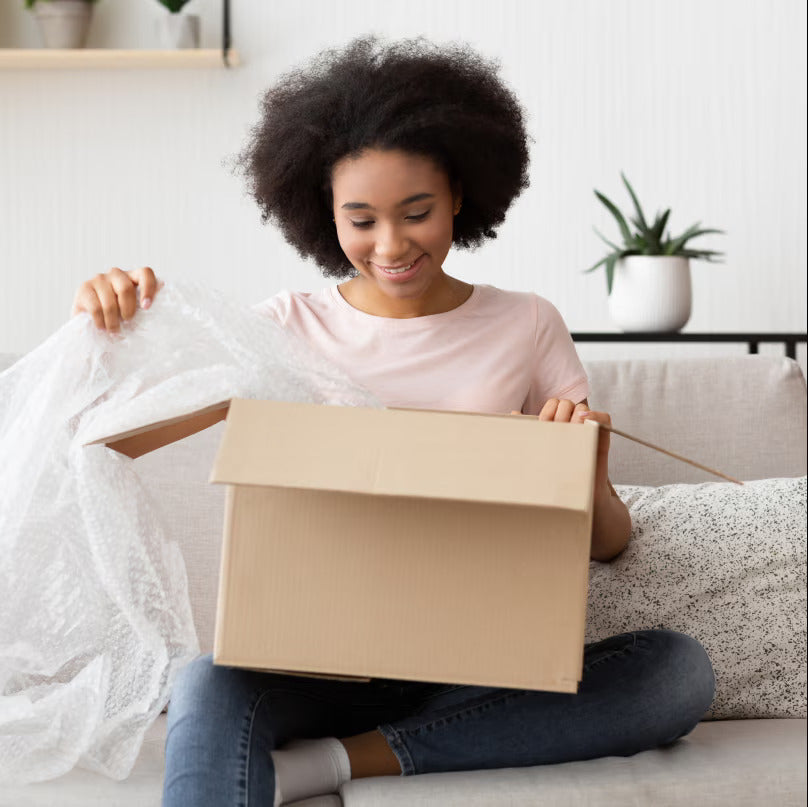 Woman opening a cardboard box in a cozy living room.