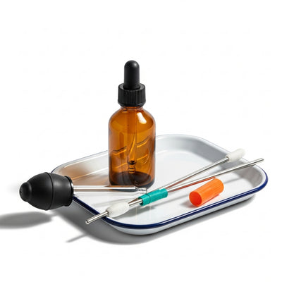 Brown glass dropper bottle with accessories on a white tray